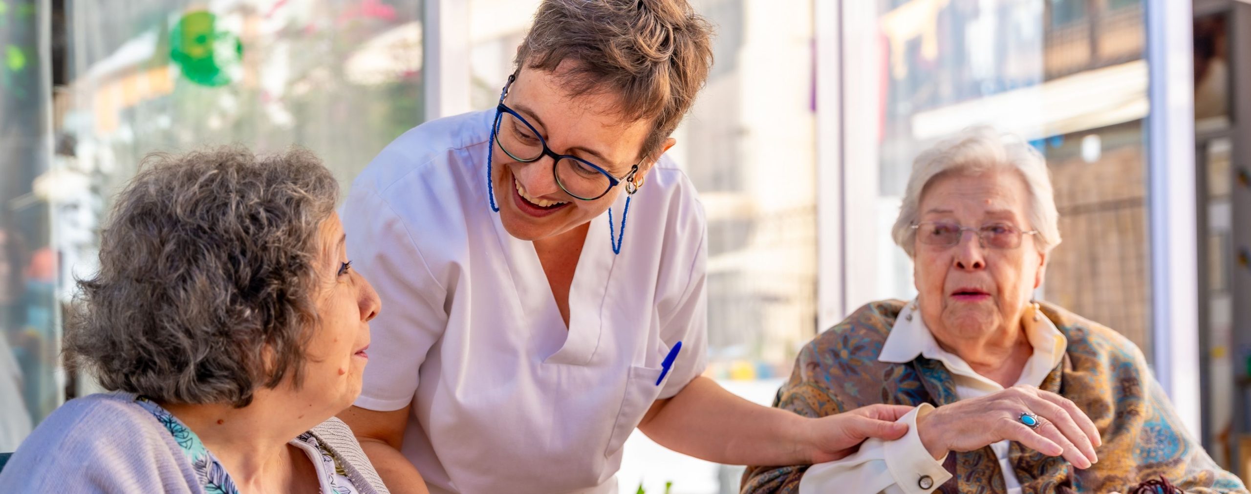 A caregiver and residents share refreshments at Willow Brook in Delaware, Ohio, used as the full-width background image on the Careers page.