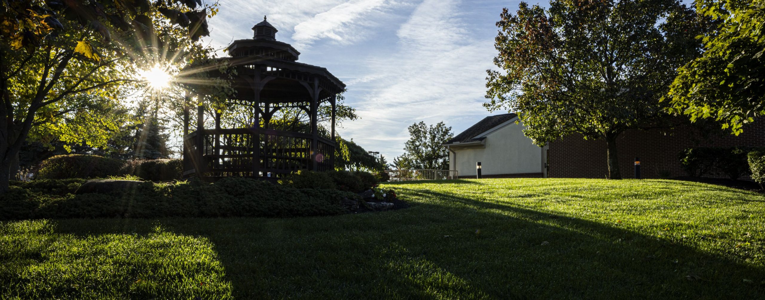 Wide banner of the Willow Brook Home gazebo at sunset in Columbus, Ohio, capturing the peaceful campus setting of this senior living community.