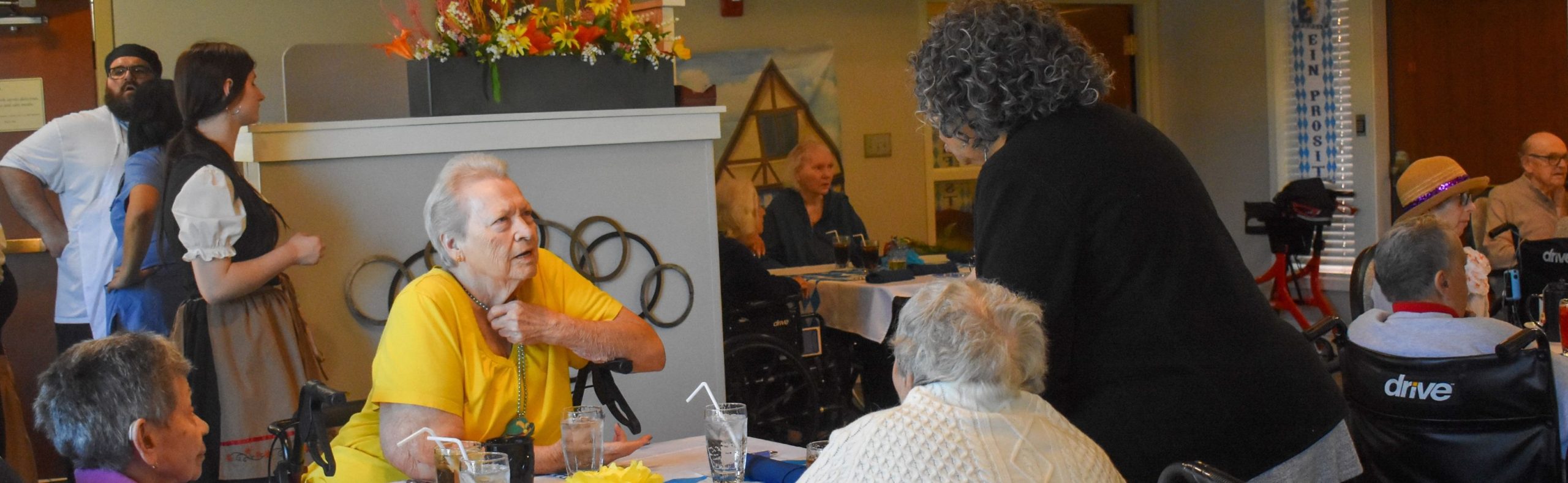 Wide desktop banner of the Heritage dining room at Willow Brook Home in Columbus, Ohio, where servers and residents share daily mealtime moments.
