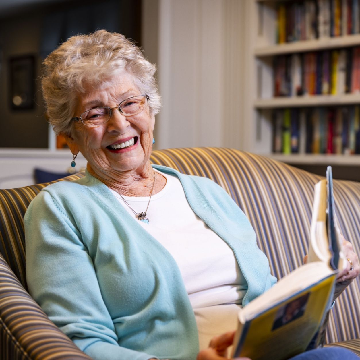 A resident smiles while reading at Willow Brook in Delaware, Ohio, used as the Home page header circle image for this senior living community.