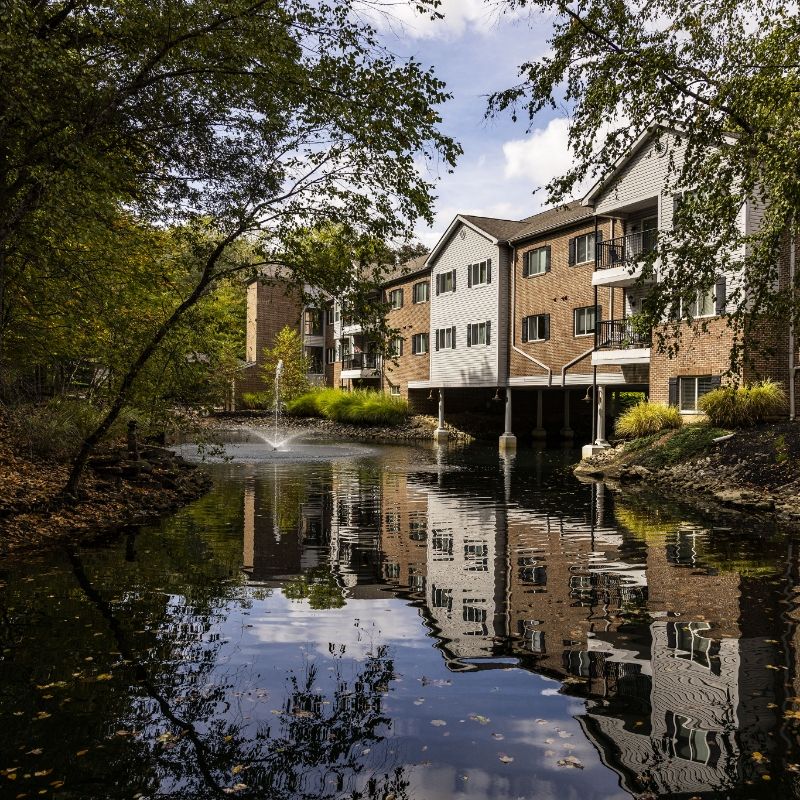 View of Willow Brook Village in Delaware, Ohio, used as the mobile header for the locations page, capturing the community's signature pond and apartments.