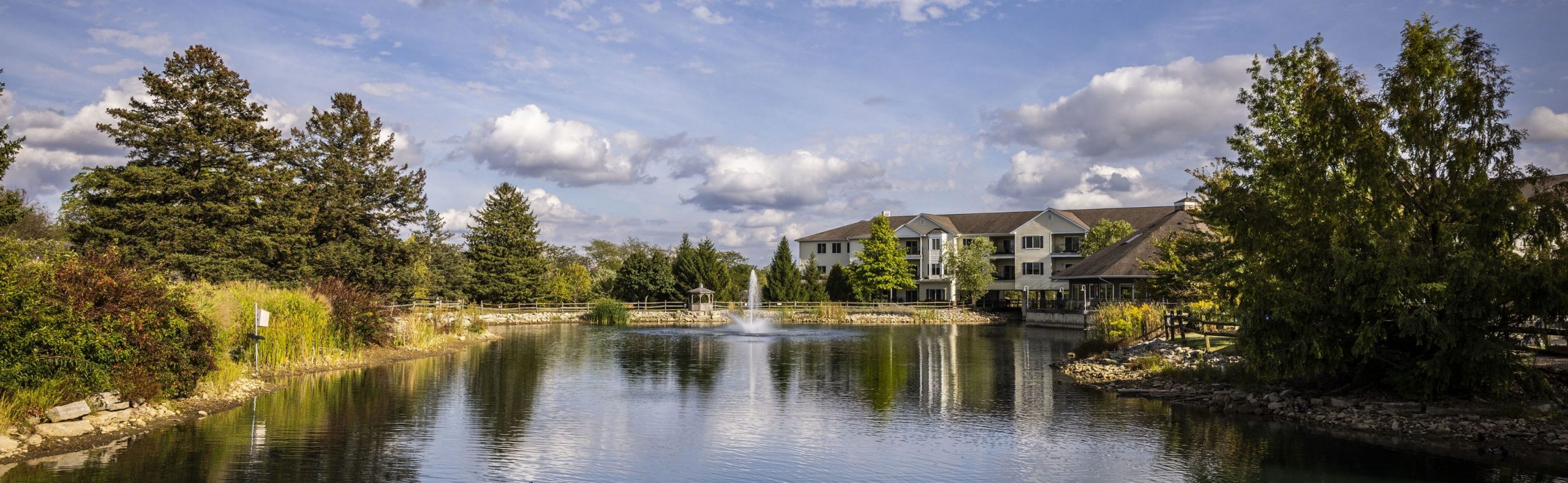 Wide desktop banner of Willow Brook Run in Delaware, Ohio, with the residences reflected in the pond, used as the floor plans page header.