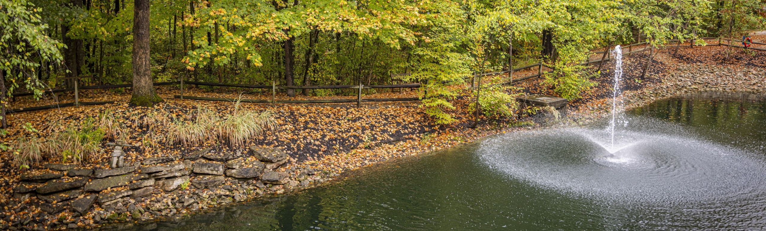Wide pond and fountain view at Willow Brook Village in Delaware, Ohio, used as a full-width background image on the contact page.