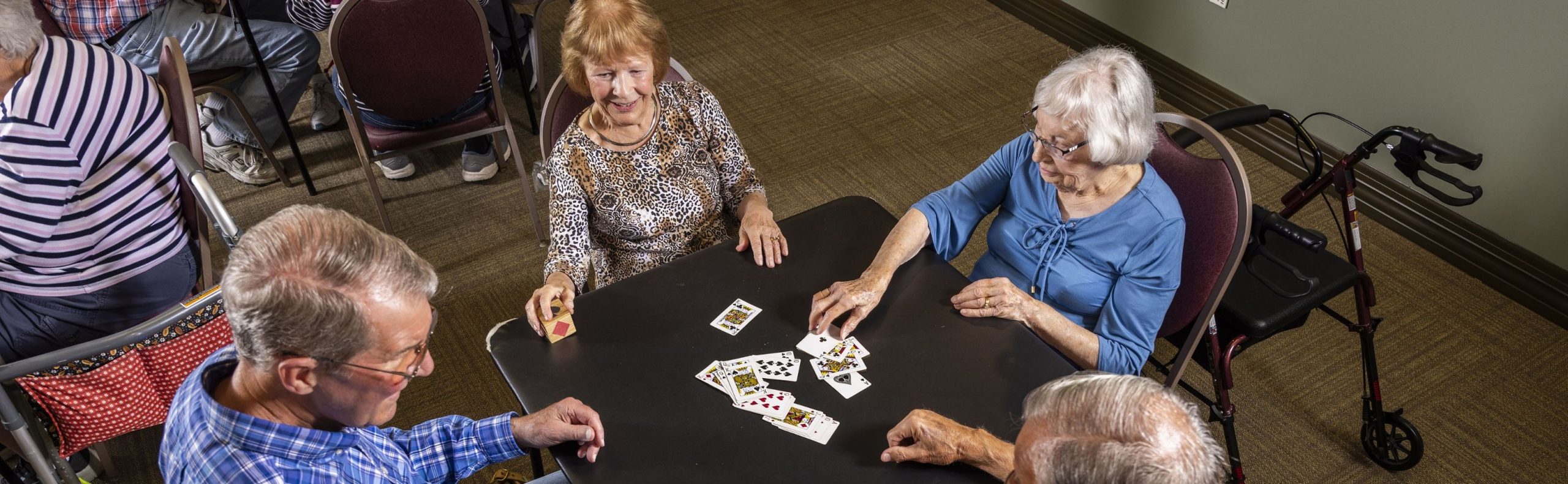 Wide desktop banner of residents playing cards at Willow Brook Village in Delaware, Ohio, used as the Life Enrichment page header.