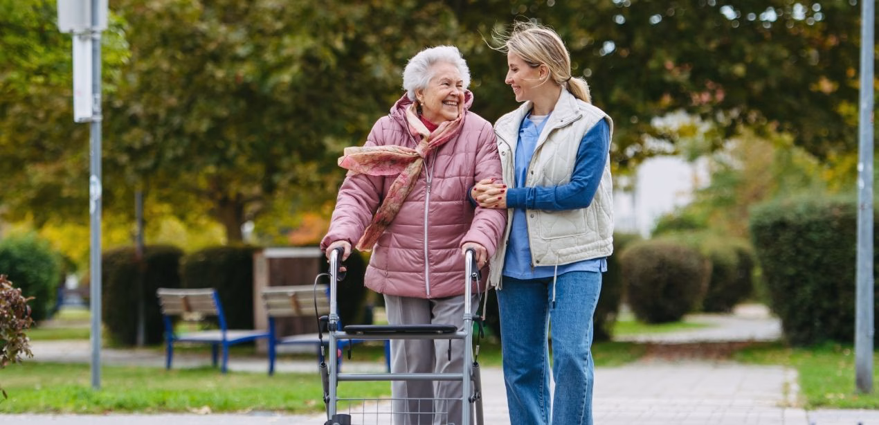 A transitional living resident walks the campus with her caregiver, reflecting the supportive lifestyle that bridges independent and assisted living at Willow Brook in Delaware, Ohio.