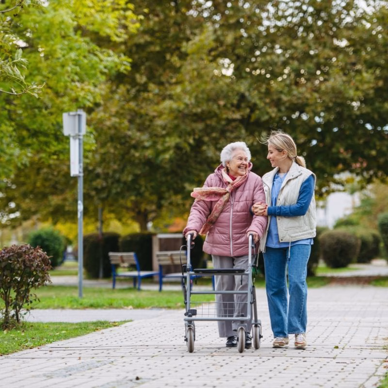 A Willow Brook resident enjoys an outdoor walk with a caregiver, illustrating the transitional living lifestyle that supports independence with hands-on help in Delaware, Ohio.