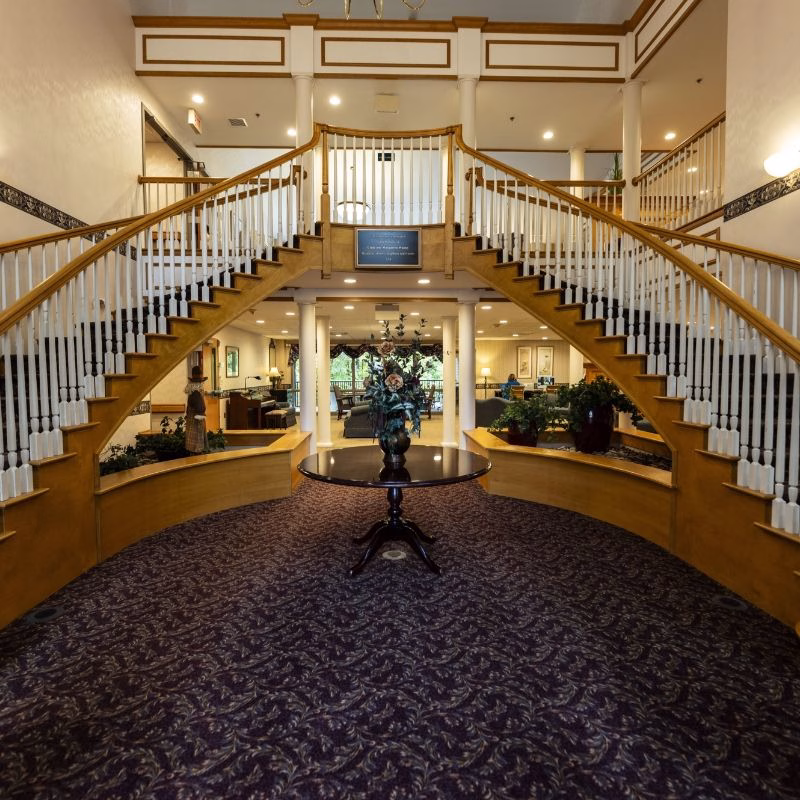 The grand atrium at Willow Brook Village in Delaware, Ohio, with its dual staircases sets a refined tone for visitors exploring floor plan options at this senior living community.