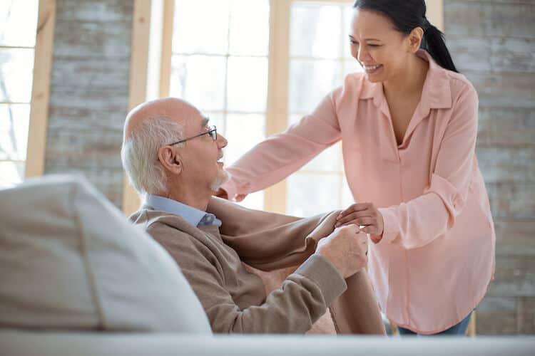 A senior caregiver giving a blanket to her father.