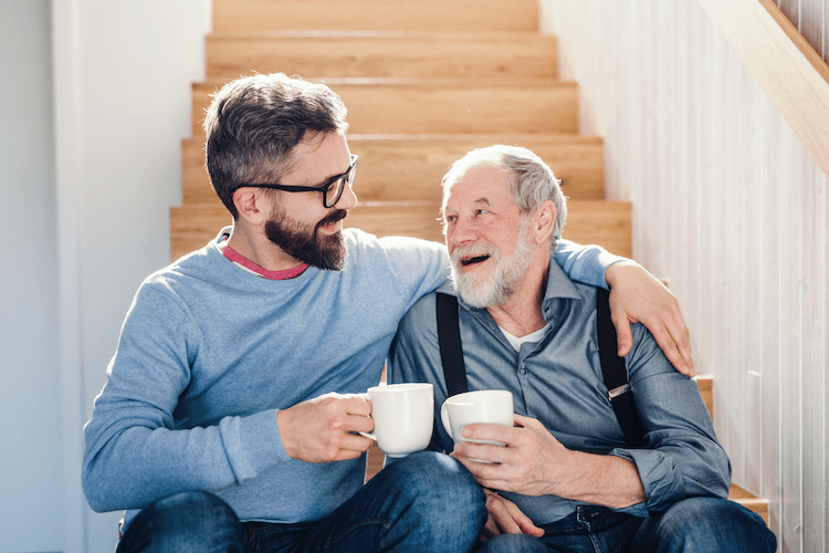 A senior man being helped along walking bars by a physical therapist at a senior rehab center.